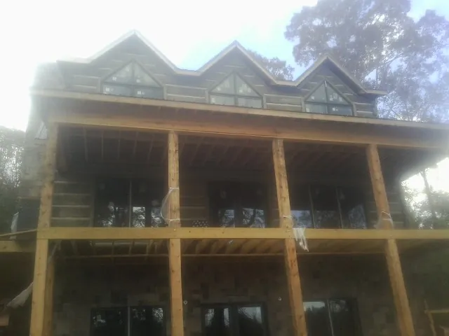Dormers and porch framing on a large log home under construction — Roof Coating work by our crew in The Plains
