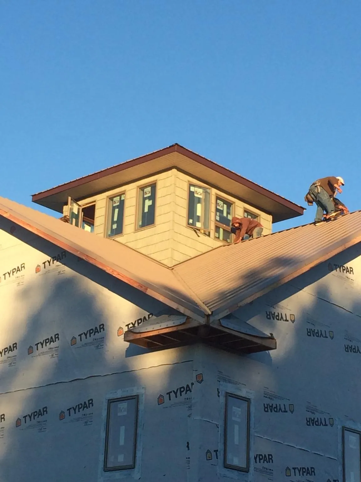 Roofers working around a rooftop cupola on a new metal roof at sunset — Roof Waterproofing in The Plains by Roofing Brothers